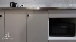 Eine Küche mit Mikrowelle, Schränken und Wasserkocher.