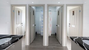 Eine Hotellobby mit einer zentralen Durchgangszone, weiß gefliesten Wänden und einem Marmor-Rezeptionsschalter.