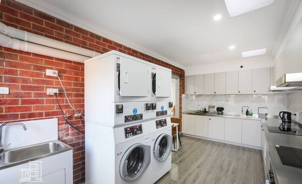 A compact kitchen with a brick wall, a washing machine, and a sink.