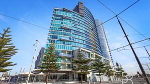 Um edifício moderno de arranha-céus com fachada curva, várias varandas e fachada de vidro.