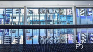 Um edifício moderno com grandes janelas que refletem edifícios altos ao redor.