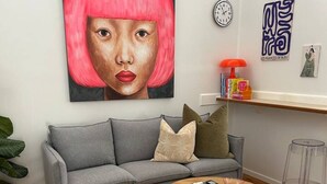 A modern living room with a grey sofa, a round wooden coffee table, a woven rug, and a wicker chair. - 2BR Home with Private Backyard, Free Parking, Fast Wi-Fi - 3-Min Walk to Yarraville Village (Yarraville)