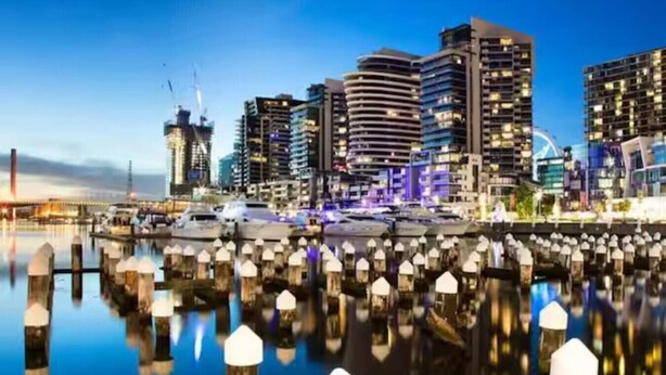 A waterfront cityscape with modern high-rise buildings, a marina with boats, and a clear sky. - Luxurious Docklands Escape| 1BR Apartment with Pool, Gym, Sauna, Balcony & Fast Wi-Fi (Docklands)