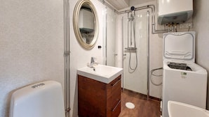 A bathroom with a white sink, wooden vanity, a mirror, a shower, and a toilet.