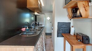 A compact kitchen with a wooden countertop, a sink, a microwave, and a toaster.