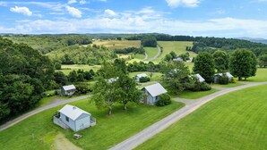 A rural landscape with several houses surrounded by lush green fields and trees. - Hillside Hideout Log Cabin For 2!  Cabin 10 (Fancy Gap)