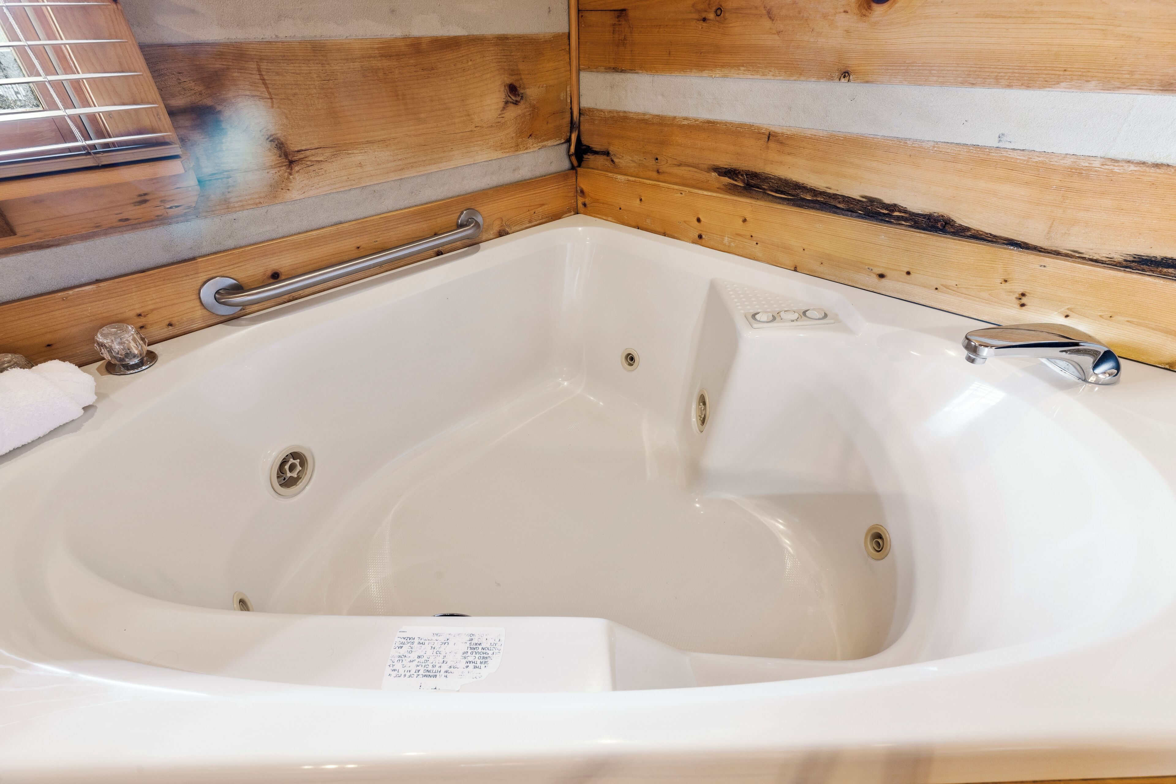 A white bathtub with a metal grab bar, a faucet, and a drain.