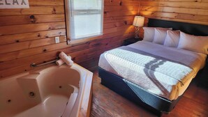A wooden cabin room with a bed, a window with blinds, a lamp, and a bathtub.