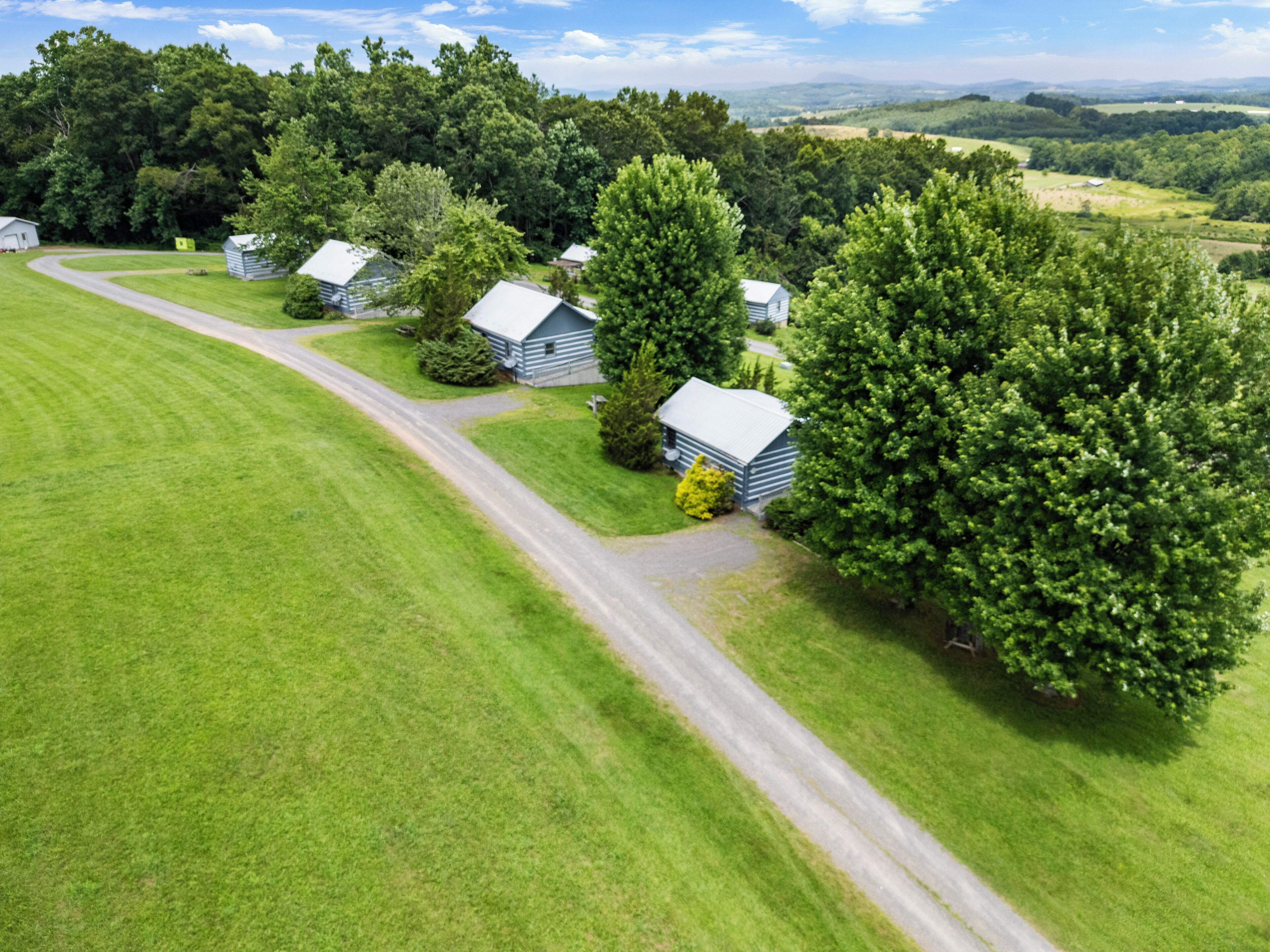 A rural landscape with several cabins and a large tree.