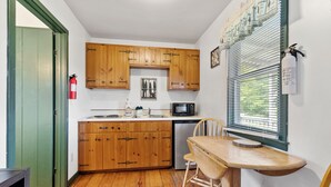 A compact kitchen with wooden cabinets, a microwave, and a sink.