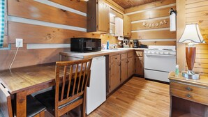 A wooden kitchen with a microwave, stove, and sink.