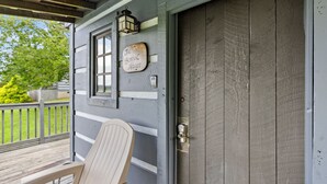 A porch with a wooden chair, a door with a metal handle, and a sign that reads "The School House."