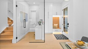 Ein modernes Interieur mit einer Treppe, einer Glaskonstruktion und einem Essbereich mit einem schwarz-weißen Teppich.