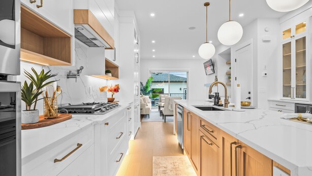 Eine moderne Küche mit weißen Schränken, Holzdetails und Pendelleuchten.