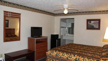 Ein Hotelzimmer mit Bett, Schreibtisch, Fernseher, Spiegel und Deckenventilator.