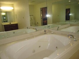 A bathroom with a large bathtub, two sinks, and a mirror.