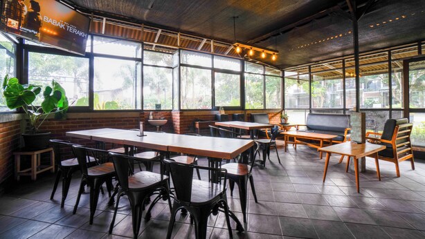 A spacious indoor dining area with large windows, wooden tables, and black chairs. - Puri Saras Syariah (Lembang)