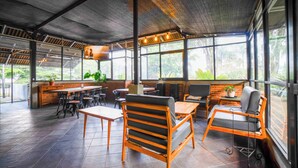 A spacious indoor area with a high ceiling, large windows, and a mix of seating arrangements including tables and chairs. - Puri Saras Syariah (Lembang)