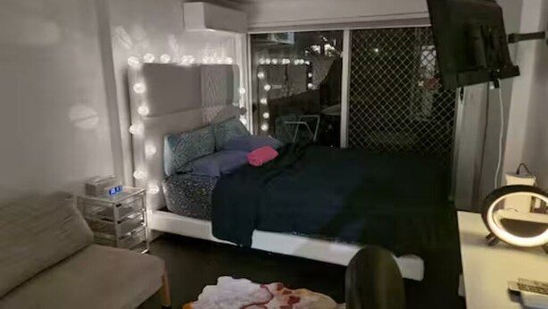 Une chambre à coucher avec un lit, une table de chevet et un miroir avec éclairage intégré.