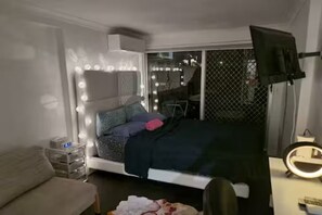 Ein Schlafzimmer mit Bett, Nachttisch und einem beleuchteten Spiegel.