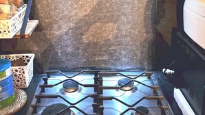 Une cuisine équipée d’une cuisinière à gaz, d’un four à micro-ondes et d’une hotte en acier inoxydable.