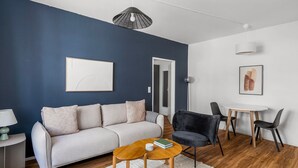 A modern living room with a sofa, a coffee table, a chair, and a dining table.