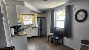 A compact kitchen with a microwave, refrigerator, and a small dining area with a bench.