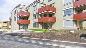 A modern apartment building with balconies, a landscaped garden, and a paved street. - Blueground | Saatlen, balcony, nr Zürich Zoo (Zurich)