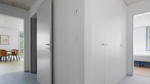 A modern hotel room with a large wardrobe, a dining area with chairs, and a view of greenery outside. - Blueground | Saatlen, balcony, nr Zürich Zoo (Zurich)