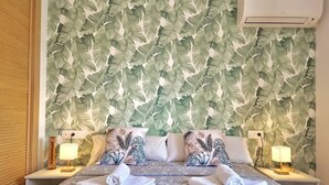 A hotel room with a bed, two nightstands with lamps, and a wall with a leafy pattern.