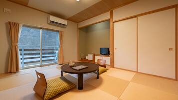 Una habitación japonesa tradicional con suelo de tatami, una mesa de tatami, un televisor y puertas correderas.
