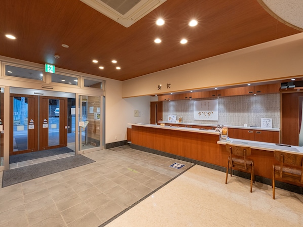 A reception area with a wooden counter, a seating area with chairs, and a glass door entrance.
