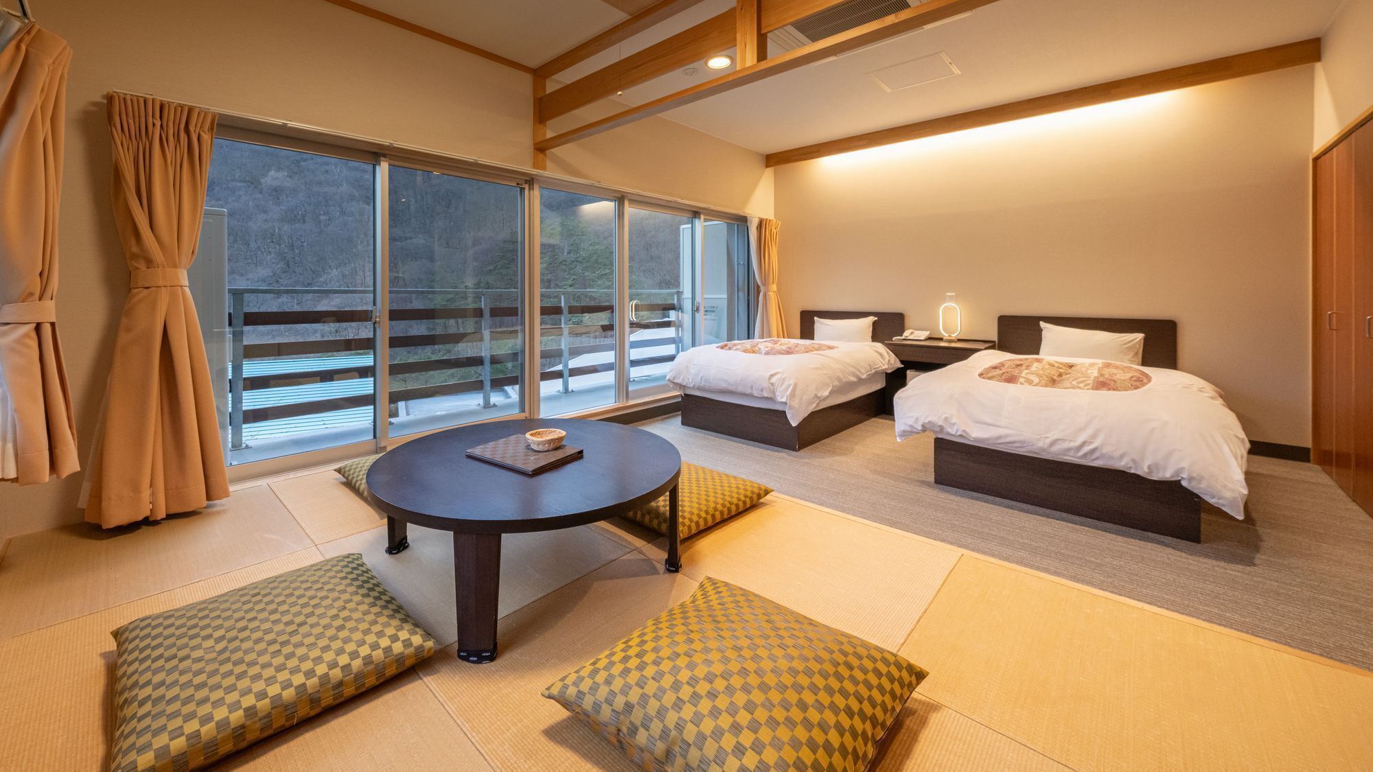Ein Hotelzimmer mit zwei Betten, einem runden Tisch und Blick ins Freie.