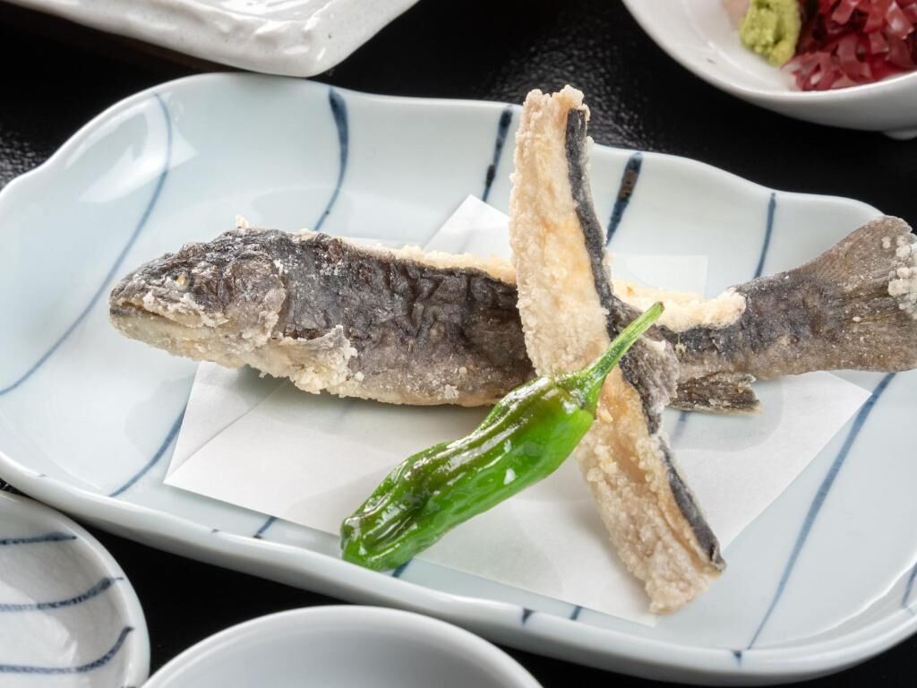A plate with two fish and a green chili.