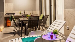 A dining area with a table, chairs, and a small round table with drinks. There is a gas cylinder and a plant on the floor. - Modern Family Villa Mia with Private Pool (Radeki Polje)
