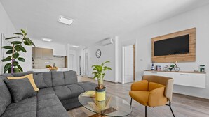 A modern living room with a sectional sofa, a glass coffee table, a yellow plant, and a mustard-colored armchair. - Modern Family Villa Mia with Private Pool (Radeki Polje)