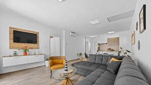 Una sala de estar moderna con un sofá seccional gris, una mesa de centro de vidrio y un sillón amarillo.