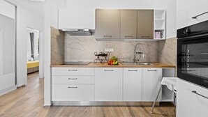 Una cocina moderna con armarios blancos, salpicadero de mármol y horno negro.