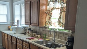 A kitchen with wooden cabinets, a microwave, a sink, and a coffee maker.