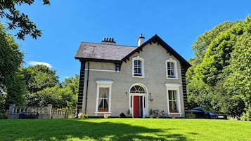 A two-story house with a red door, a balcony, and a car parked in front.