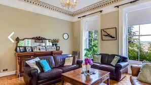 A living room with two leather sofas, a wooden coffee table, and a chandelier.