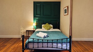 A room with a bed, a nightstand, a lamp, and a framed picture on the wall.