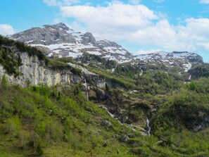 Een bergachtig landschap met een waterval, rotsachtige kliffen en schaarse begroeiing.