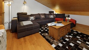 A cozy living room with a sofa, a coffee table, and a lamp. - Mon Abri B by Interhome (Les Diablerets)