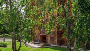 A rustic wooden building with a front entrance, surrounded by lush greenery and trees. - Mon Abri B by Interhome (Les Diablerets)