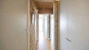 Un couloir avec un plafond en bois, des murs blancs et une porte sur le côté droit.