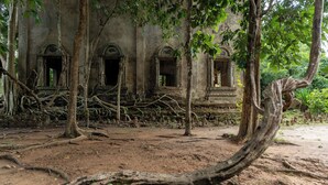 An ancient temple with three arched doorways, surrounded by dense vegetation and overgrown with roots. - Samprasob Resort (Sangkhla Buri)