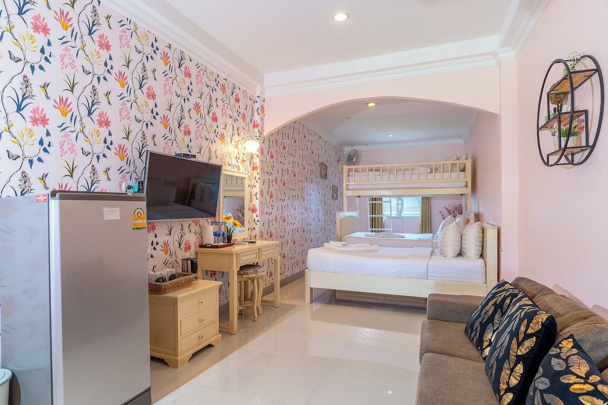 A bedroom with a bunk bed, a desk with a computer, a TV, and a dresser.