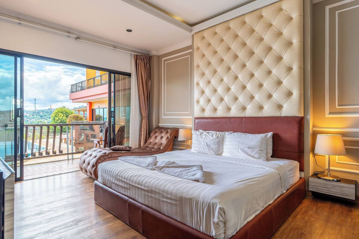 A spacious bedroom with a large bed, a balcony with a view, and a modern design.