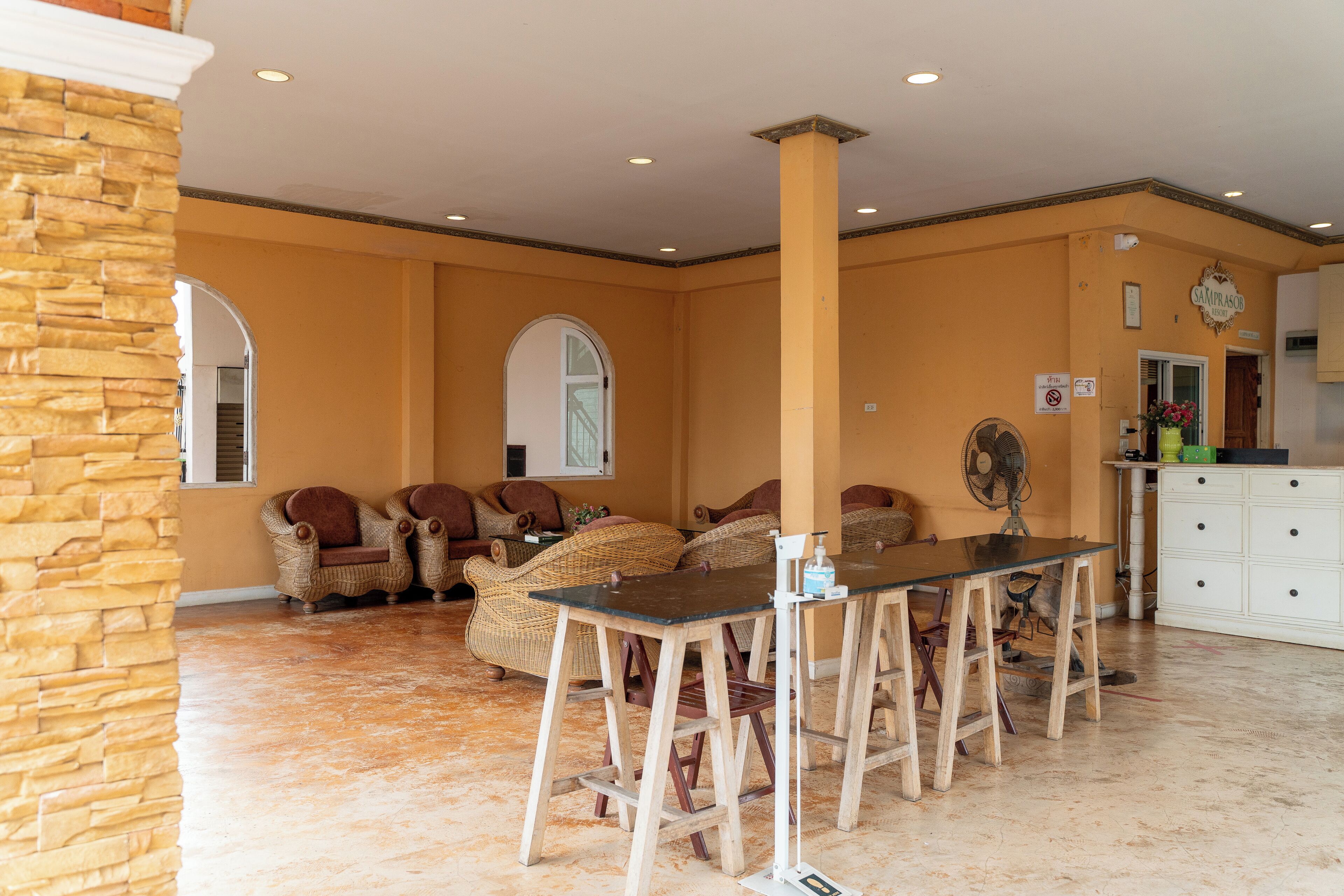Amplia habitación con una pared de acento de piedra, muebles de mimbre, una mesa de comedor con taburetes tipo bar y un armario blanco.